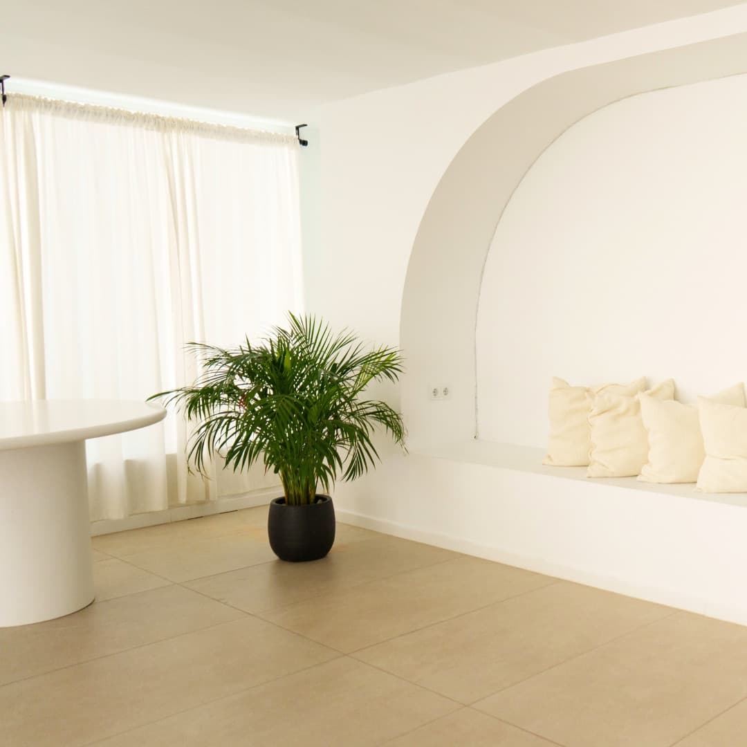 El arco con cojines, la planta y las cortinas con luz natural del estudio de AR Studio